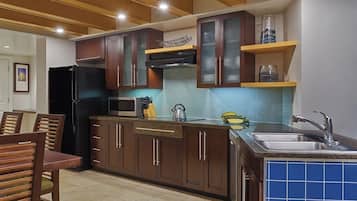A modern kitchen with dark wooden cabinets, a stainless steel sink, and a microwave.