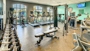 Een sportschool met loopbanden, gewichten en krachttrainingsapparatuur.