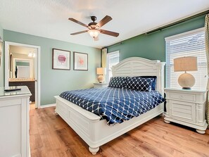 A bedroom with a bed, a nightstand, a dresser, a ceiling fan, and a window with blinds. - Spacious 8BR Luxury Home, Pool,Spa, By Disney (Kissimmee)
