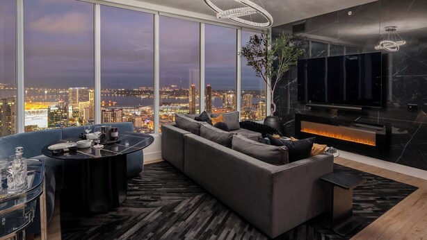 A modern living room with a large sofa, a dining table, and a fireplace. - 41st Floor! 2bdr w/ Luxury Amenities & Balcony Skylux Penthouse by Avantstay (San Diego)