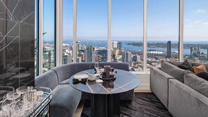 A modern room with a large window, a round table with dinnerware, and a grey sofa. - 41st Floor! 2bdr w/ Luxury Amenities & Balcony Skylux Penthouse by Avantstay (San Diego)