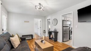 A modern living room with a dark leather sofa, a wooden coffee table, and a kitchen area with stainless steel appliances. - Cozy&Convenient Modern Home • Private Fenced Yard (Springfield)
