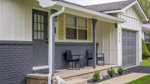 A residential house with a covered porch, two black chairs, and a garage. - Cozy&Convenient Modern Home • Private Fenced Yard (Springfield)