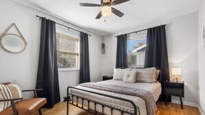 A bedroom with a bed, a chair, a bedside table, a ceiling fan, and a window with curtains. - Cozy&Convenient Modern Home • Private Fenced Yard (Springfield)