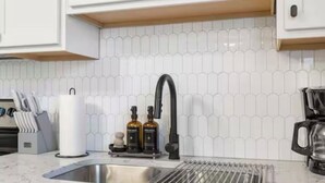 A kitchen with a stainless steel sink, a modern faucet, and a tiled backsplash. - Cozy&Convenient Modern Home • Private Fenced Yard (Springfield)