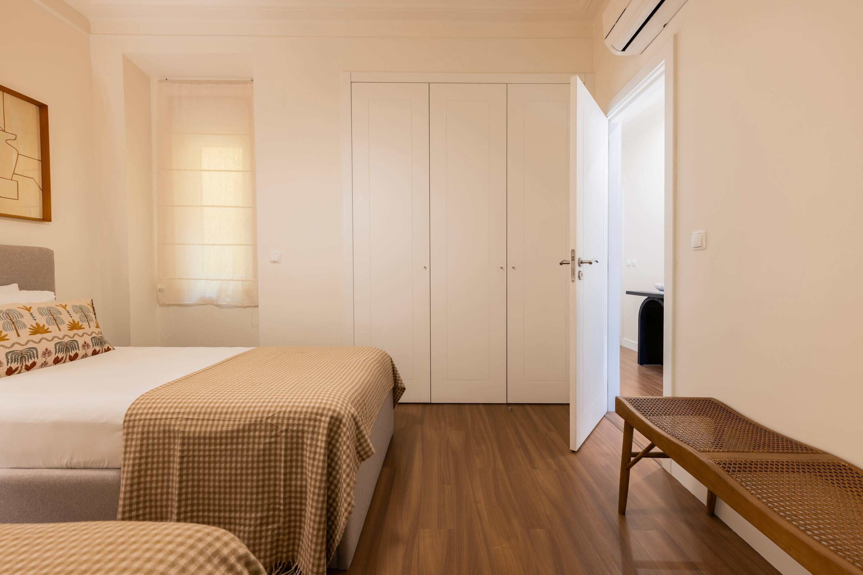A hotel room with a bed, a bench, a wardrobe, and a window.