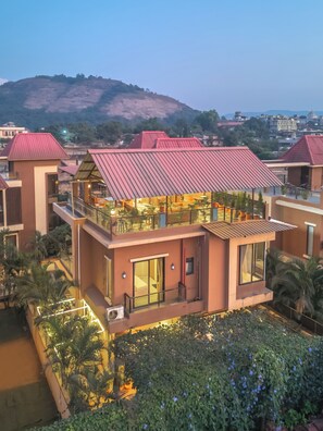 A modern hotel with a flat roof, large windows, and a balcony with outdoor seating. - RETRO VILLA  (Lonavala)