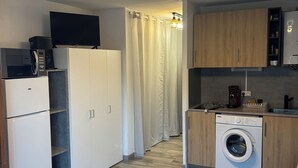 Een kleine keuken met een magnetron, koelkast en wasmachine.