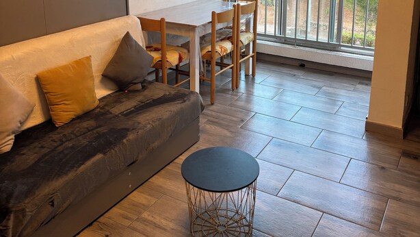 Een moderne woonkamer met een bank, een rond bijzettafeltje en een eethoek met stoelen.