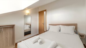 Una habitación de hotel con una cama grande, un armario de madera, un espejo y una puerta.