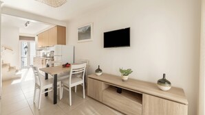 Una cocina moderna con comedor, televisor de pantalla plana y una escalera que lleva a otra habitación.