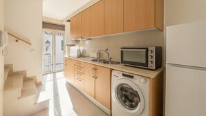 Una cocina con armarios de madera, microondas, lavadora y refrigerador.