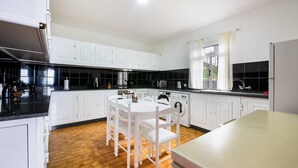 Cozinha moderna com armários brancos, uma ilha central e uma mesa de jantar com cadeiras.