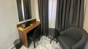 A hotel room with a desk, chair, and a small round table. - Ringruby Hotel Value County (Lekki)