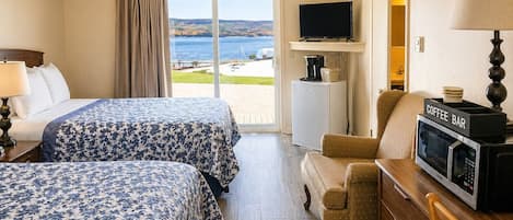 A hotel room with two beds, a TV, a coffee bar, and a view of the outdoors.