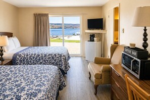 Ein Hotelzimmer mit zwei Betten, einem Fernseher, einer Kaffeestation und Blick ins Freie.