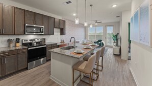 A modern kitchen with granite countertops, stainless steel appliances, and a central island with bar stools. - Ocean Paradise 1BR/1BA Near Atlantic Beach (Jacksonville)