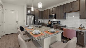A modern kitchen with granite countertops, stainless steel appliances, and dark wood cabinets. - Ocean Paradise 1BR/1BA Near Atlantic Beach (Jacksonville)