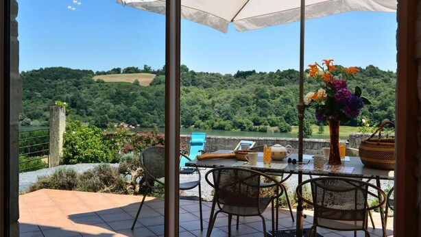 A patio with a table, chairs, an umbrella, and a view of a green landscape. - ENDRIMONS - VIELLESEGURE (VIELLESEGURE)