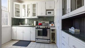 Uma cozinha moderna com armários brancos, fogão de aço inoxidável e micro-ondas.