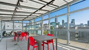 A rooftop terrace with a glass enclosure, red chairs, and a table. - Studio apt walkable to Oracle Park (San Francisco)