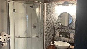 Une salle de bain avec une douche à parois de verre, un lavabo blanc et un meuble-lavabo avec des tiroirs.