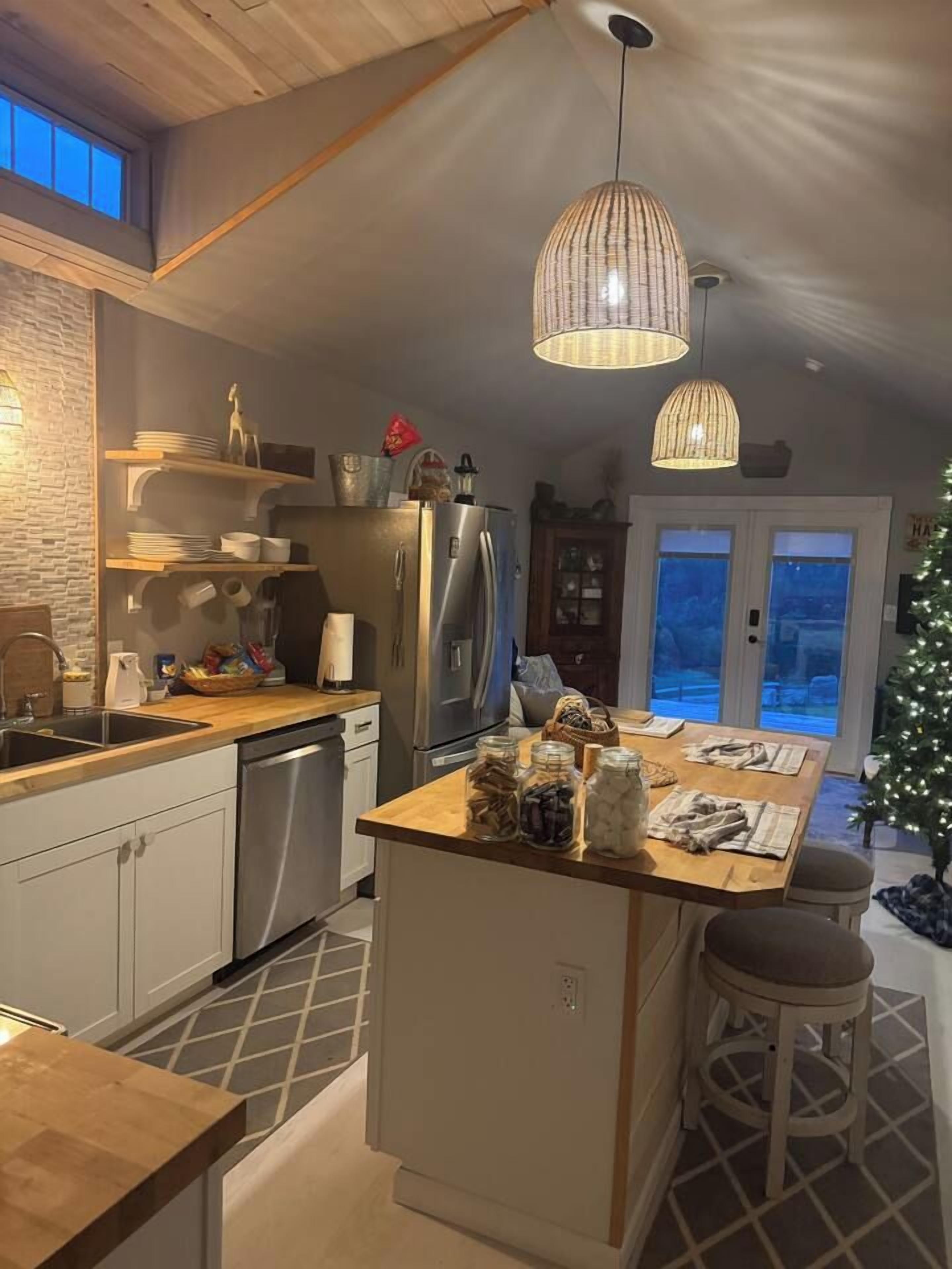 Cozinha com ilha central, eletrodomésticos de aço inoxidável e iluminação pendente.