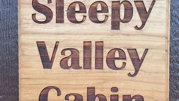 Une pancarte en bois portant l’inscription « Sleepy Valley Cabin ».