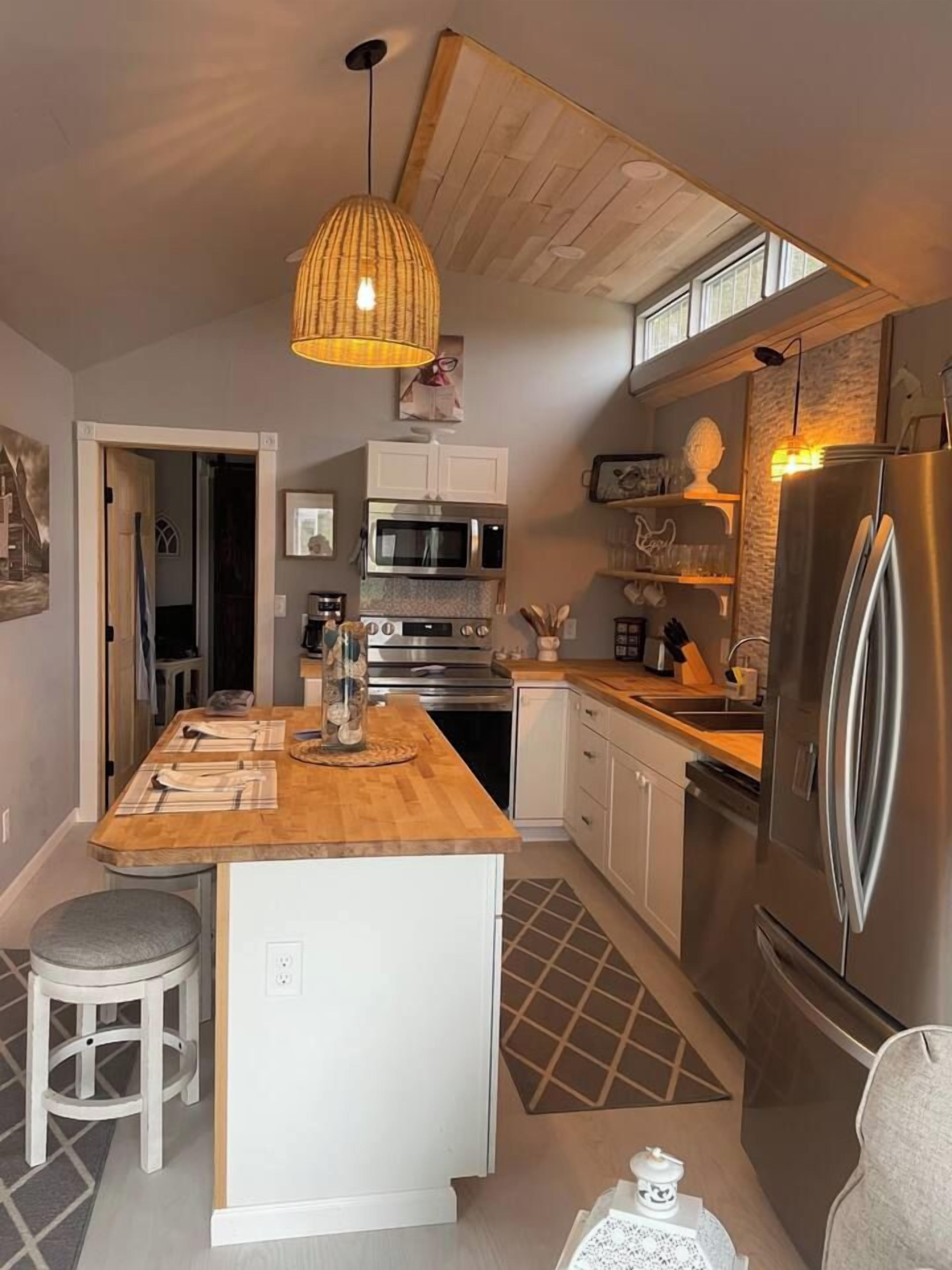 Una cucina moderna con isola centrale, elettrodomestici in acciaio inossidabile e una lampada a sospensione.
