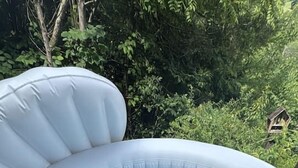 Un jacuzzi gonflable installé sur une terrasse en bois, avec un décor naturel en arrière-plan.