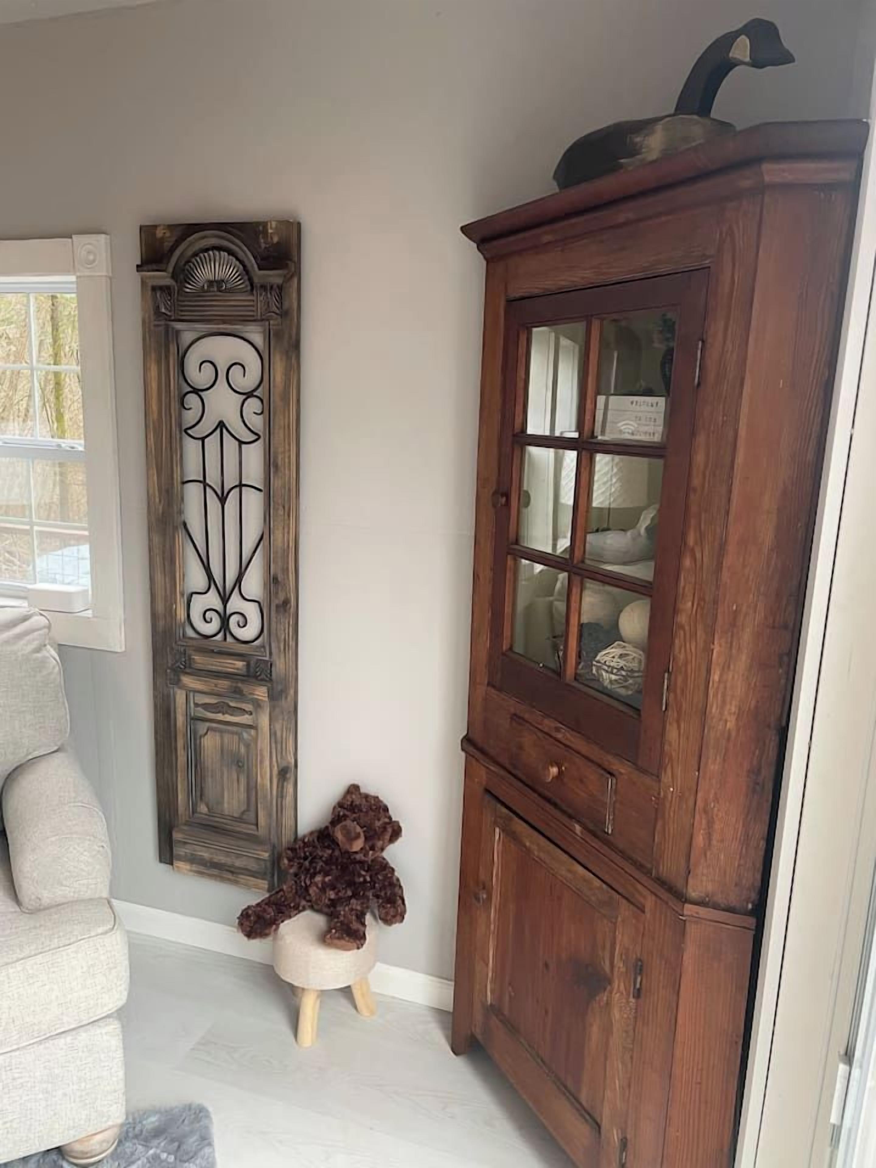 Une pièce comprenant un meuble en bois, un élément décoratif mural et un petit tabouret sur lequel est posé un animal en peluche.