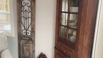 Une pièce comprenant un meuble en bois, un élément décoratif mural et un petit tabouret sur lequel est posé un animal en peluche.
