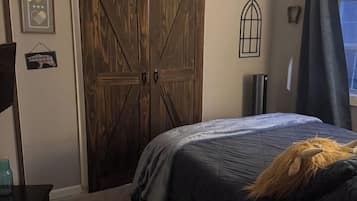 A bedroom with a bed, a ceiling fan, a sliding barn door, and a window with curtains.