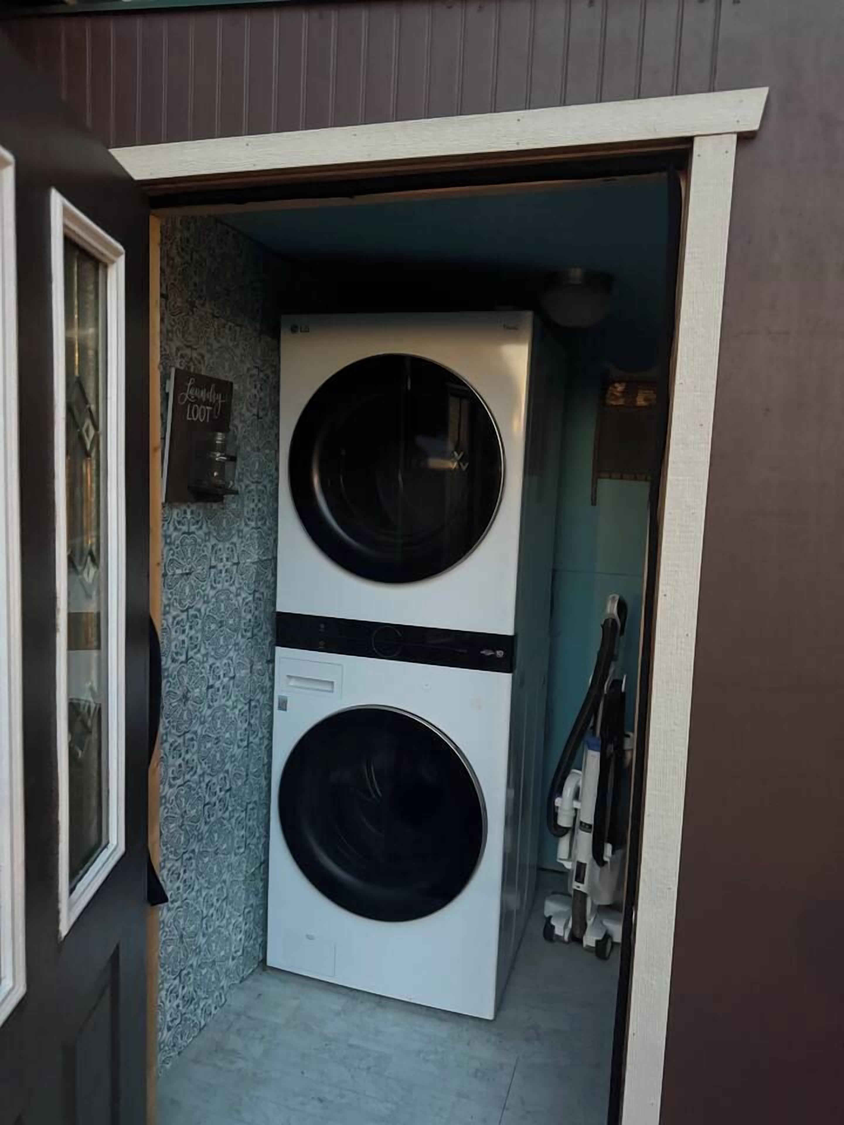 A laundry room with two stacked washing machines and a sign that reads 'Laundry Room.'
