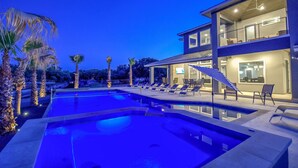 A modern two-story building with a swimming pool, lounge chairs, and palm trees. - Lazy Haven Resort: Luxury Lakefront Estate on Lake LBJ with Private Pool Hot Tub (Kingsland)