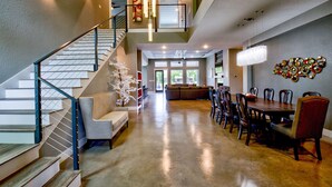 A spacious living area with a staircase, a dining table with chairs, and a decorative wall piece. - Lazy Haven Resort: Luxury Lakefront Estate on Lake LBJ with Private Pool Hot Tub (Kingsland)