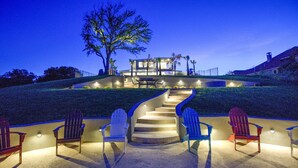 A modern house with a staircase leading to a deck, surrounded by chairs and a tree. - Lazy Haven Resort: Luxury Lakefront Estate on Lake LBJ with Private Pool Hot Tub (Kingsland)