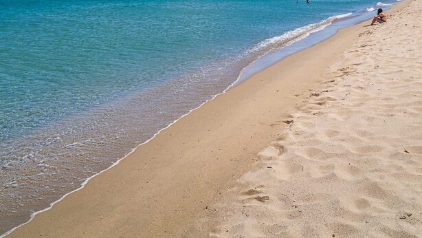 Ein Strand mit klarem türkisblauem Wasser und einem sandigen Ufer.