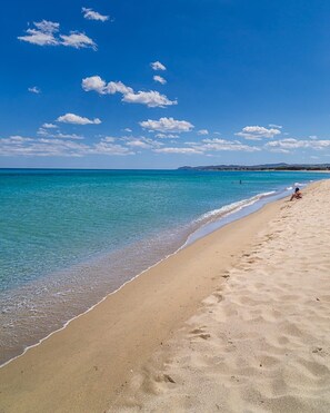 Une plage à l’eau turquoise et limpide, bordée d’un rivage sablonneux.