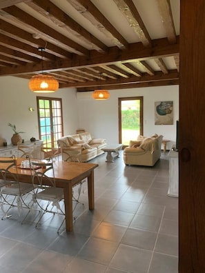 A spacious living area with a wooden ceiling, a dining table with chairs, and two sofas. - Le Gîte du Bosque - BISCARROSSE (BISCARROSSE)