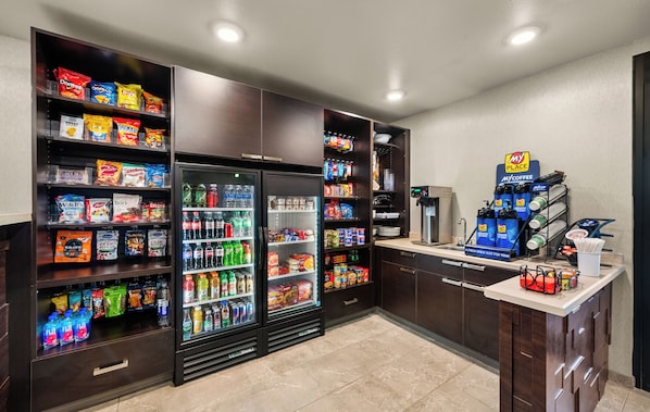 A well-stocked convenience store with shelves of snacks, beverages, and a coffee station.