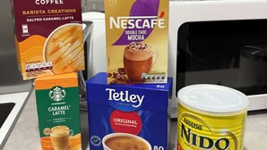 Un comptoir de cuisine avec une boîte de café Costa Coffee Barista Creations, saveur caramel salé, une boîte de Nescafe Double Choc Mocha, une boîte de Tetley Caramel Latte et une boîte de lait en poudre entier Nestlé Nido.