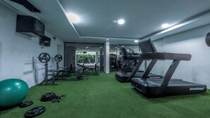 Ein Fitnessstudio mit Laufbändern, Gewichten und einem Übungsball.