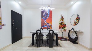 Ein Essbereich mit Tisch und Stühlen, einem großen Gemälde, einem Weihnachtsbaum und einem Spiegel an der Wand.