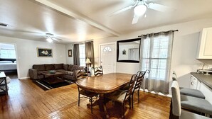Una sala de estar amplia con una mesa de comedor de madera, un sofá y un ventilador de techo.