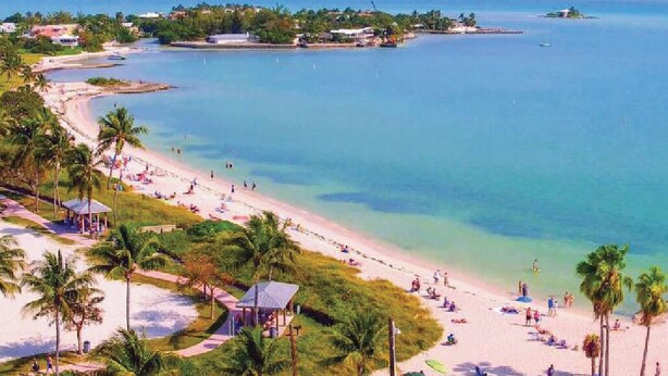 A beach with clear water, palm trees, and a few buildings in the background. - Gorgeous Coral Lagoon Villa - Top Rated Resort in Marathon w/ Boat Slip -Amazing (Marathon)