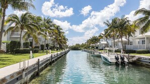 A canal lined with palm trees and white buildings, with a boat docked on the right. - Gorgeous Coral Lagoon Villa - Top Rated Resort in Marathon w/ Boat Slip -Amazing (Marathon)