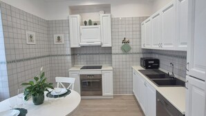 Eine moderne Küche mit weißen Schränken, einem eingebauten Backofen und einer schwarzen Spüle.