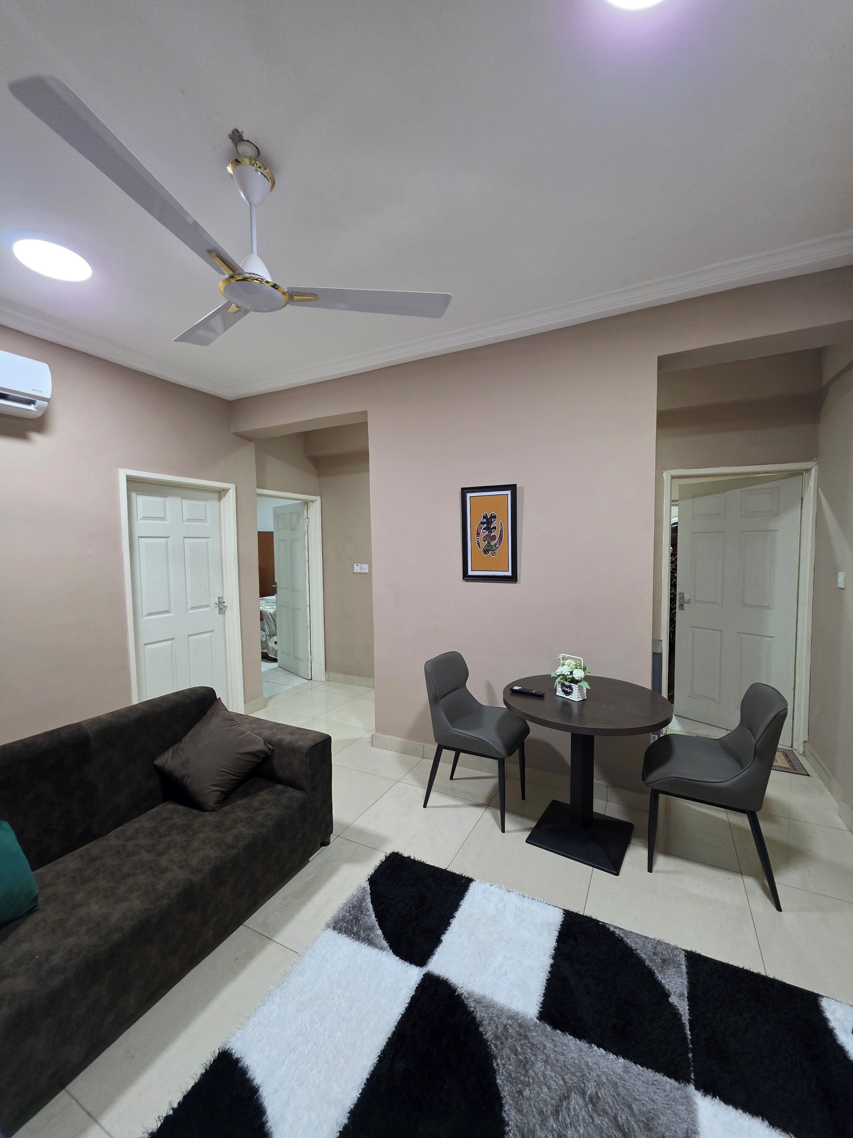 A living room with a sofa, a dining table with chairs, a ceiling fan, and a framed picture on the wall.