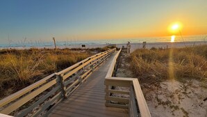 A wooden boardwalk leading to a beach with the sun setting in the background. - Direct Beachfront, Largest Balcony,4BR-4Ba, Bunks, 2 Master Beds, Full Remodel (Panama City Beach)